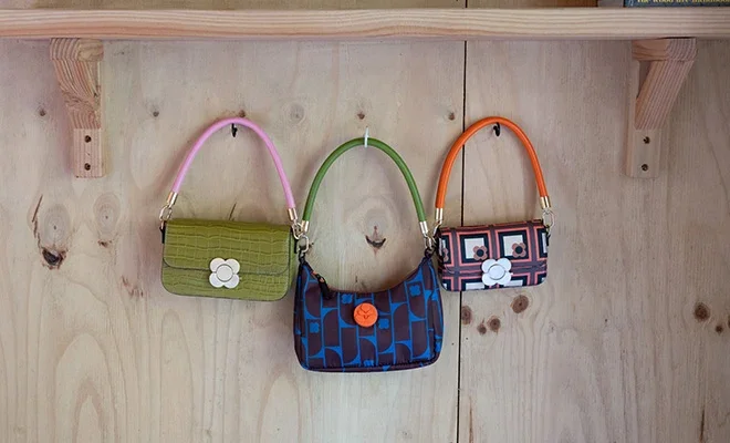 Orla Kiely bags with colourful straps hung on a wooden shelf