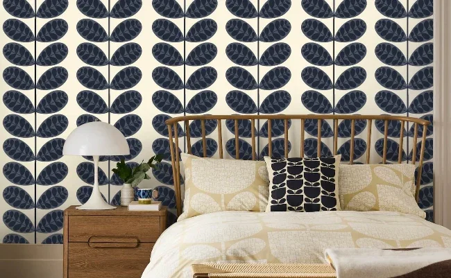 Orla Kiely navy Stem wallpaper behind a bed with cushions