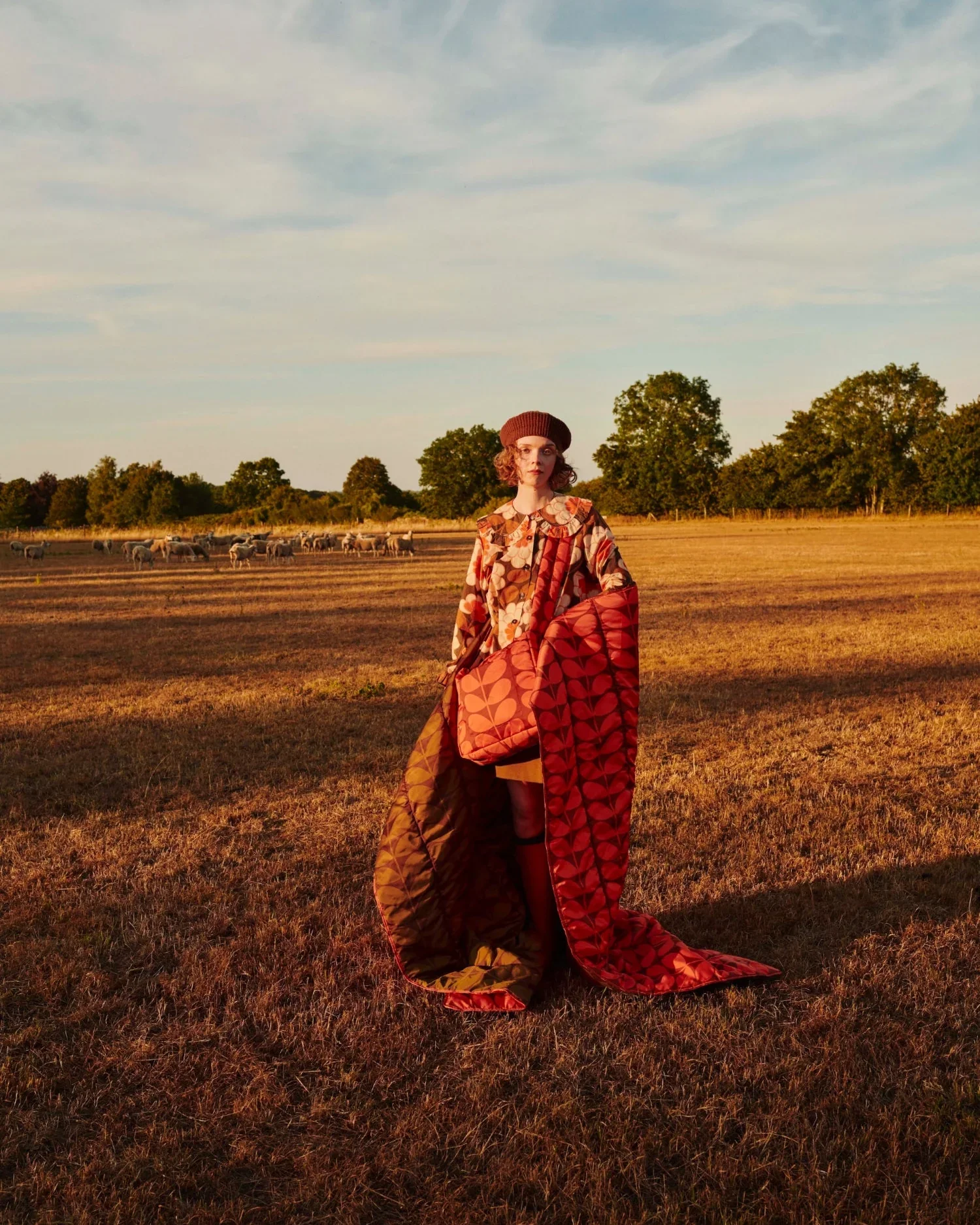 Orla Kiely AW26 look: a figure in a red and orange coat in a ploughed field
