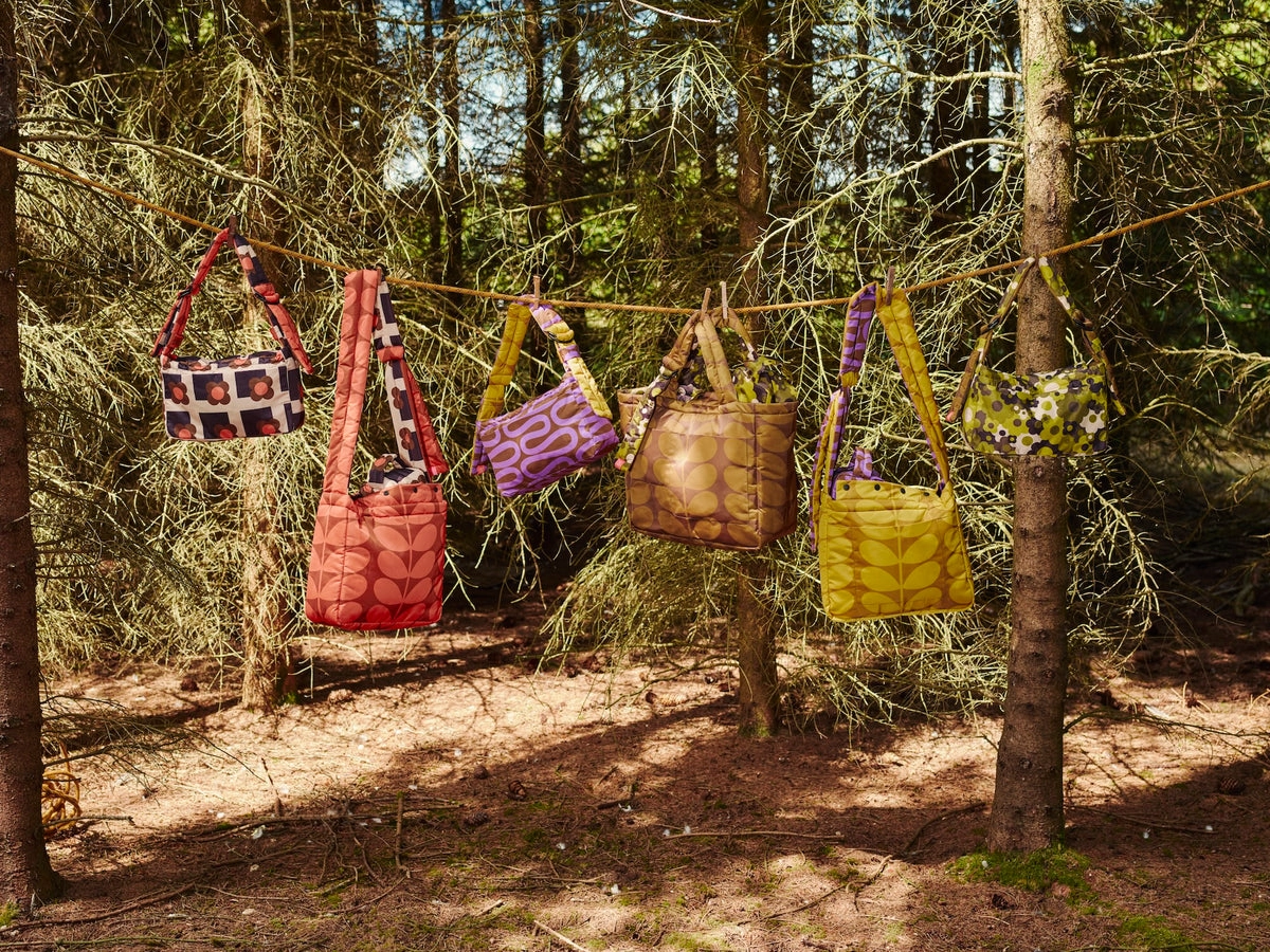 Orla Kiely quilted bags hanging from the branches of a pine forest